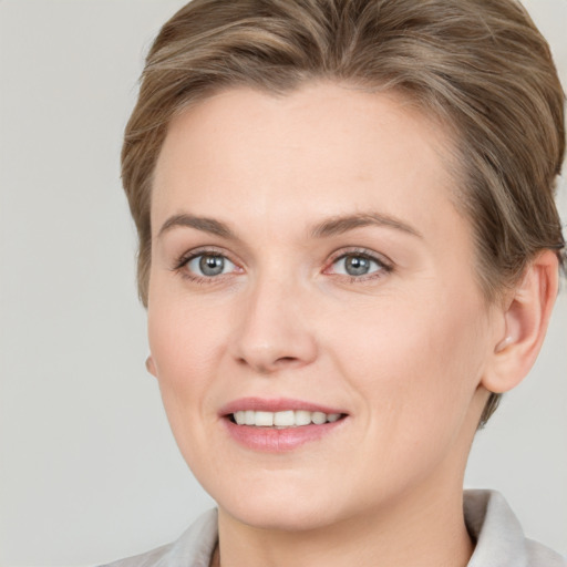 Joyful white young-adult female with short  brown hair and grey eyes