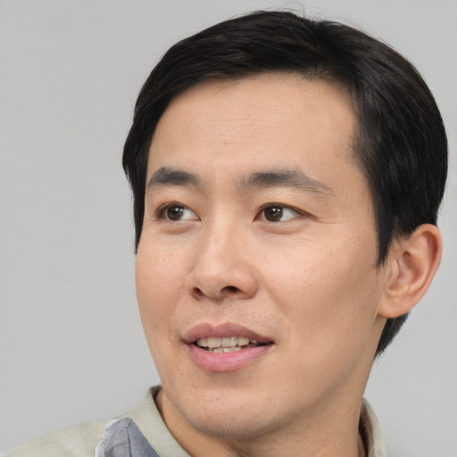 Joyful asian adult male with short  black hair and brown eyes