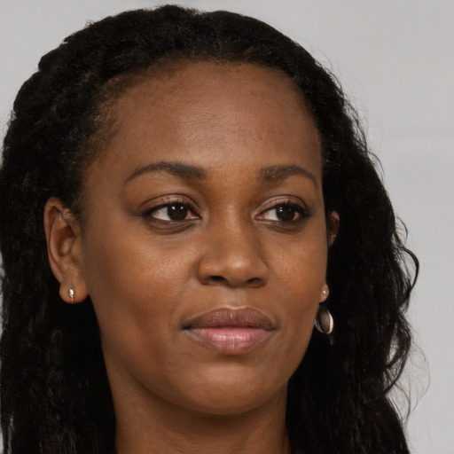 Joyful black young-adult female with long  brown hair and brown eyes