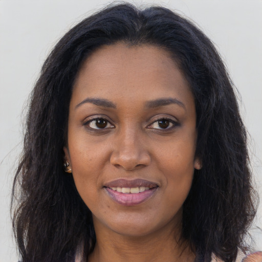 Joyful black young-adult female with long  brown hair and brown eyes