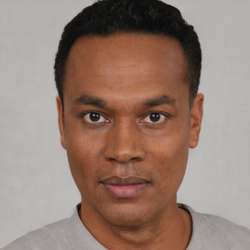 Joyful black young-adult male with short  black hair and brown eyes