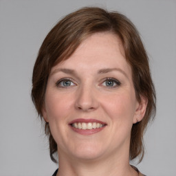 Joyful white young-adult female with medium  brown hair and grey eyes