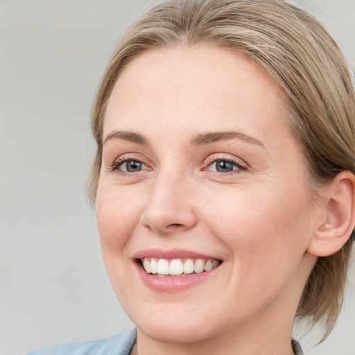 Joyful white young-adult female with medium  brown hair and blue eyes