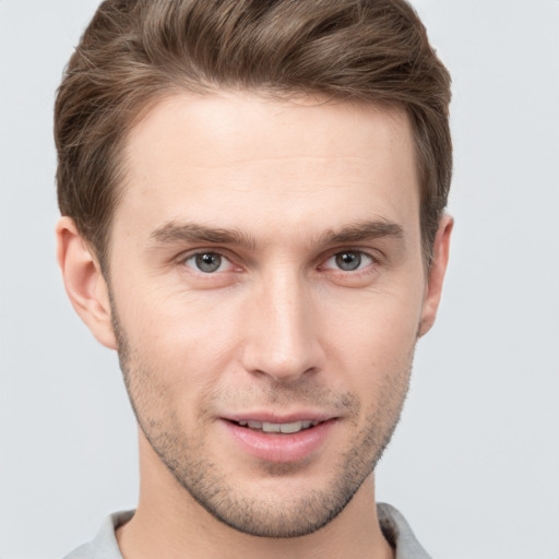 Joyful white young-adult male with short  brown hair and grey eyes