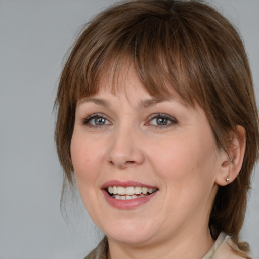 Joyful white young-adult female with medium  brown hair and grey eyes