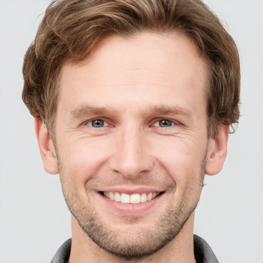 Joyful white young-adult male with short  brown hair and grey eyes