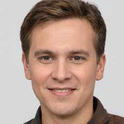 Joyful white young-adult male with short  brown hair and grey eyes