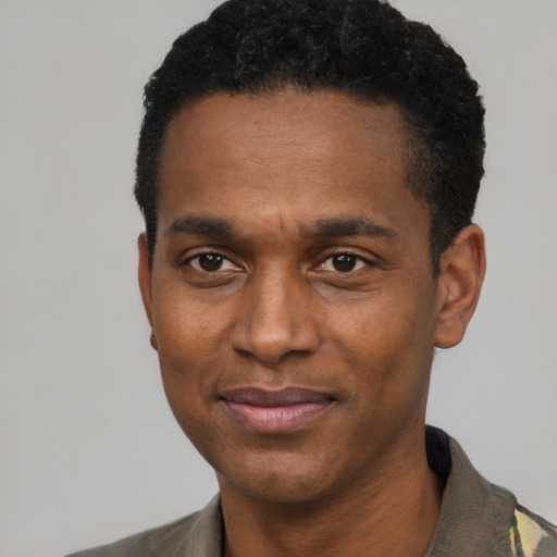Joyful black young-adult male with short  black hair and brown eyes