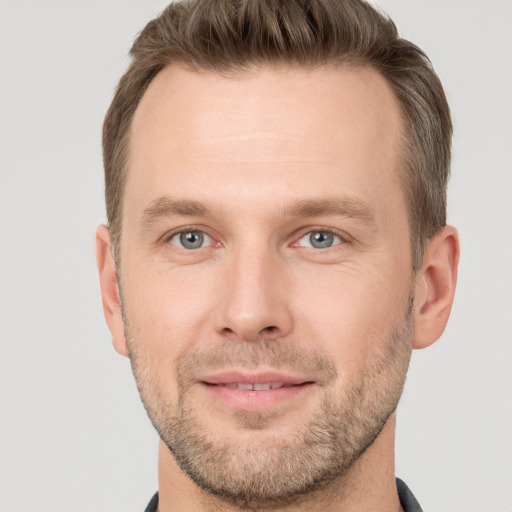 Joyful white young-adult male with short  brown hair and grey eyes