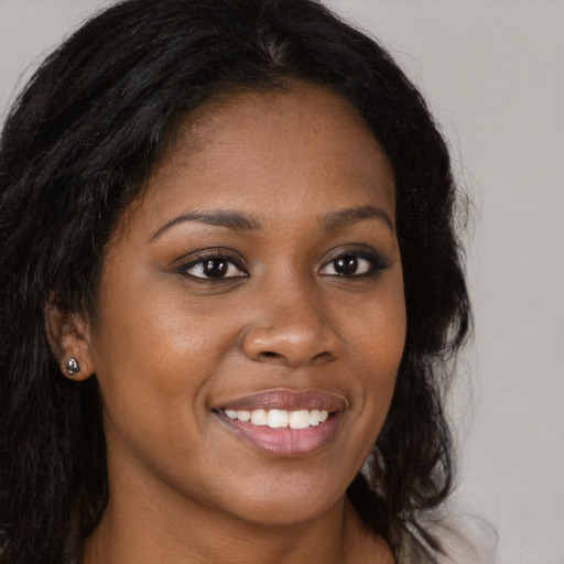 Joyful black young-adult female with long  brown hair and brown eyes