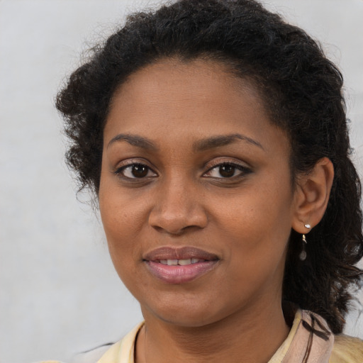 Joyful black young-adult female with long  brown hair and brown eyes
