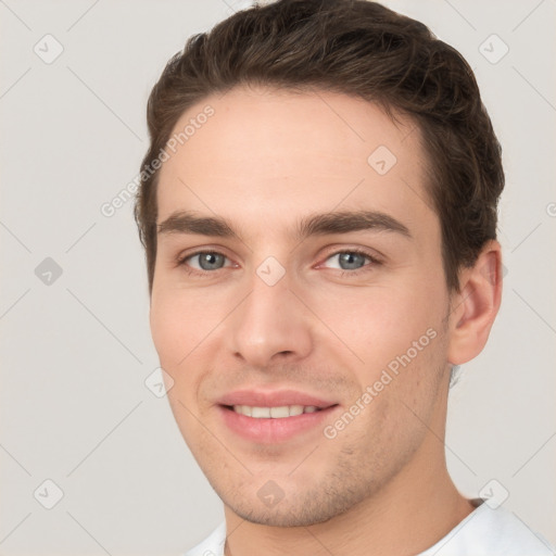 Joyful white young-adult male with short  brown hair and grey eyes