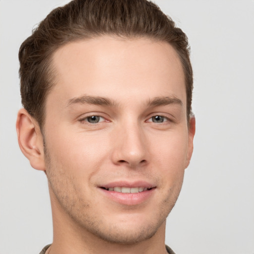 Joyful white young-adult male with short  brown hair and grey eyes