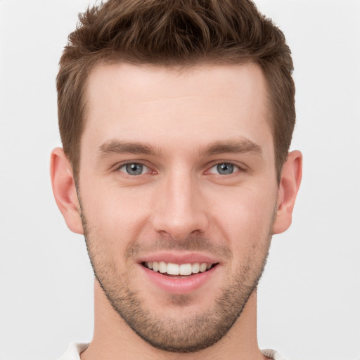 Joyful white young-adult male with short  brown hair and grey eyes