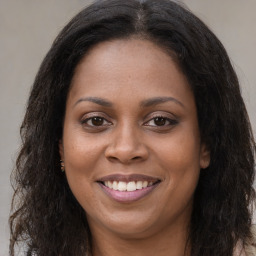 Joyful black young-adult female with long  brown hair and brown eyes