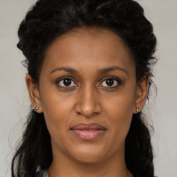 Joyful black adult female with long  brown hair and brown eyes