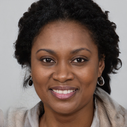 Joyful black young-adult female with long  brown hair and brown eyes