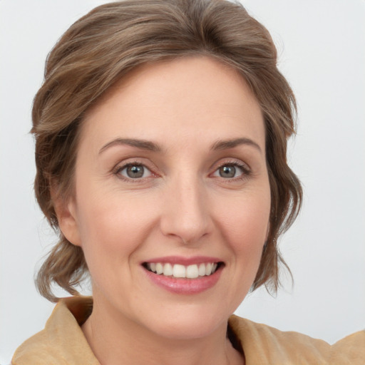 Joyful white young-adult female with medium  brown hair and grey eyes