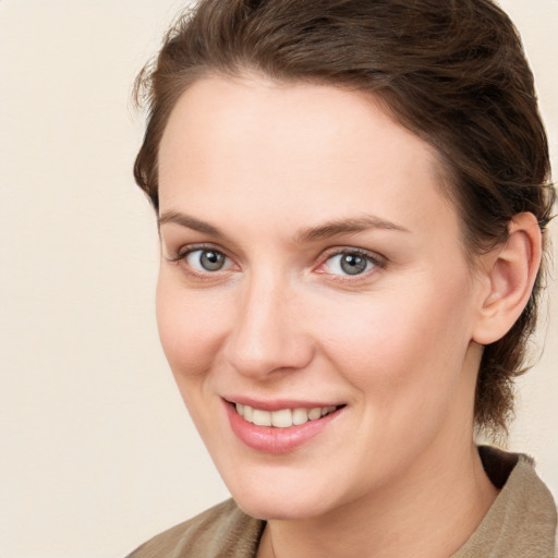 Joyful white young-adult female with medium  brown hair and grey eyes