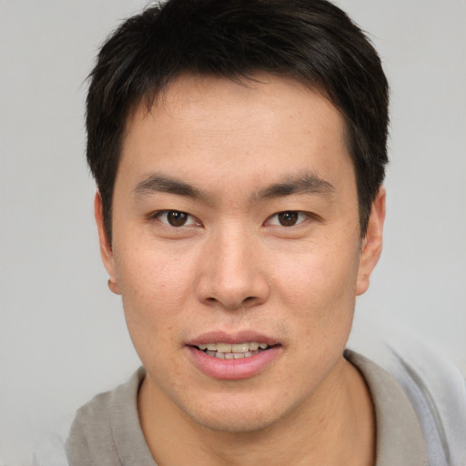 Joyful asian young-adult male with short  brown hair and brown eyes