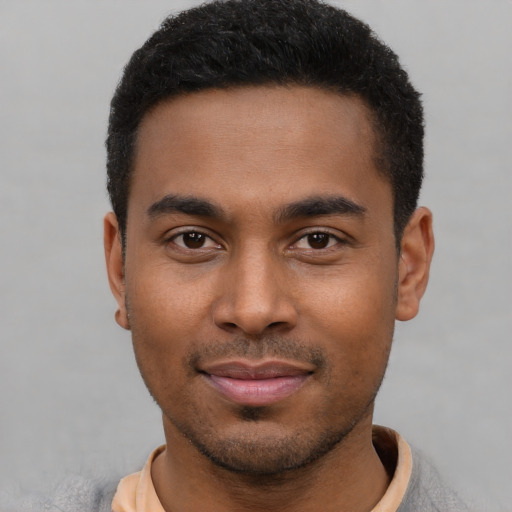 Joyful black young-adult male with short  black hair and brown eyes