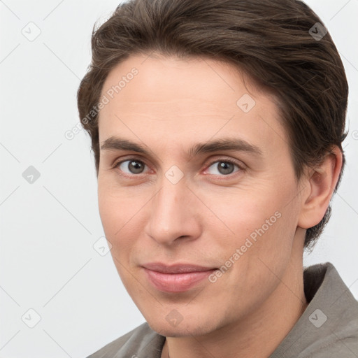 Joyful white young-adult male with short  brown hair and grey eyes