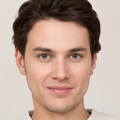 Joyful white young-adult male with short  brown hair and grey eyes