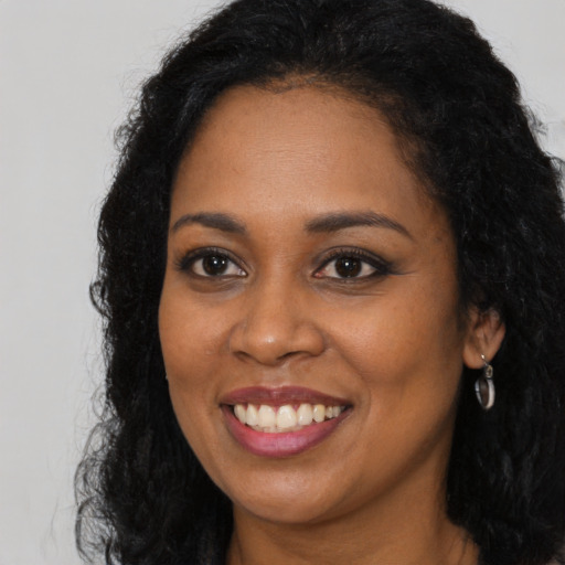 Joyful black young-adult female with long  black hair and brown eyes