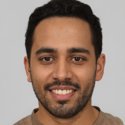 Joyful latino young-adult male with short  black hair and brown eyes