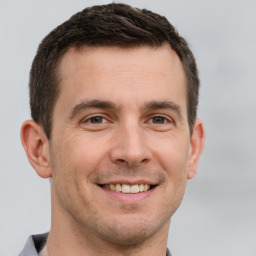 Joyful white young-adult male with short  brown hair and grey eyes