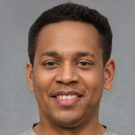 Joyful latino young-adult male with short  brown hair and brown eyes