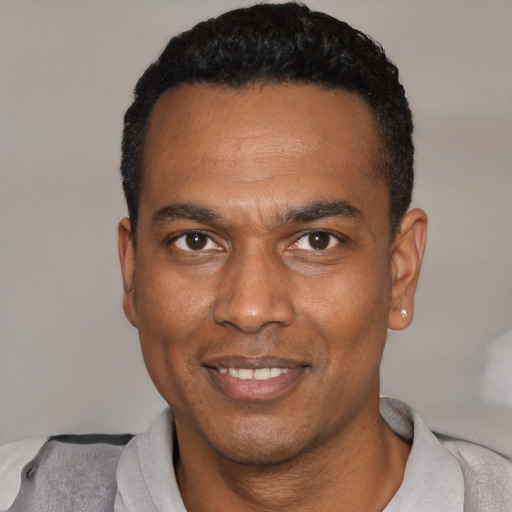 Joyful black young-adult male with short  black hair and brown eyes