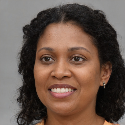 Joyful black adult female with long  brown hair and brown eyes