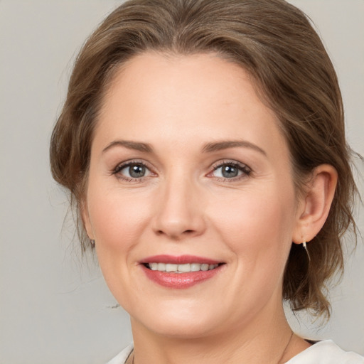 Joyful white adult female with medium  brown hair and grey eyes