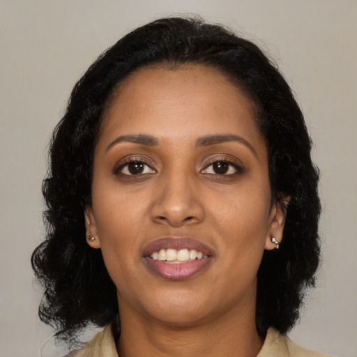 Joyful black young-adult female with long  black hair and brown eyes