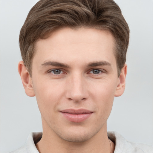 Joyful white young-adult male with short  brown hair and grey eyes