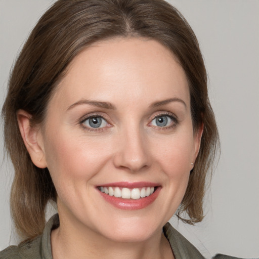 Joyful white young-adult female with medium  brown hair and grey eyes