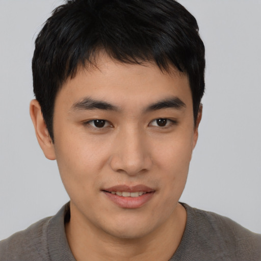 Joyful asian young-adult male with short  brown hair and brown eyes