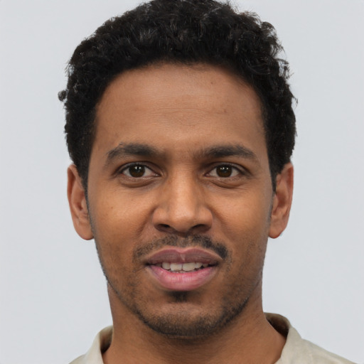 Joyful black young-adult male with short  black hair and brown eyes