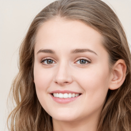 Joyful white young-adult female with long  brown hair and blue eyes