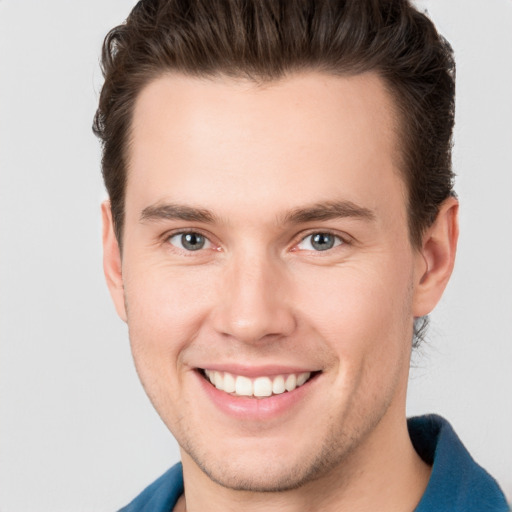 Joyful white young-adult male with short  brown hair and grey eyes