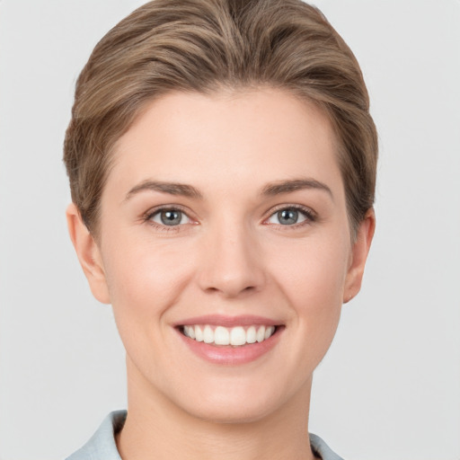 Joyful white young-adult female with short  brown hair and grey eyes