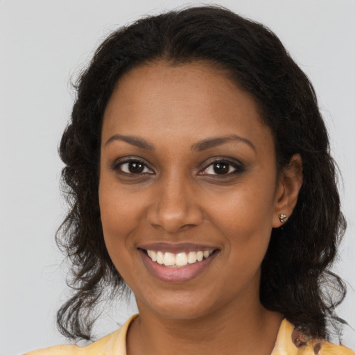 Joyful black young-adult female with long  brown hair and brown eyes