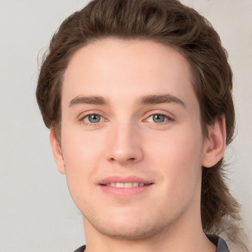 Joyful white young-adult male with medium  brown hair and grey eyes