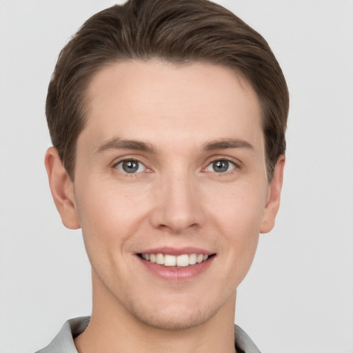 Joyful white young-adult male with short  brown hair and grey eyes