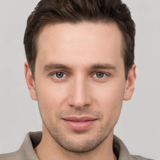 Joyful white young-adult male with short  brown hair and grey eyes