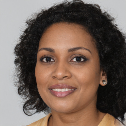 Joyful black young-adult female with long  brown hair and brown eyes