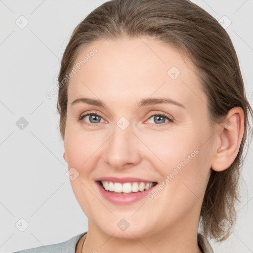 Joyful white young-adult female with medium  brown hair and grey eyes