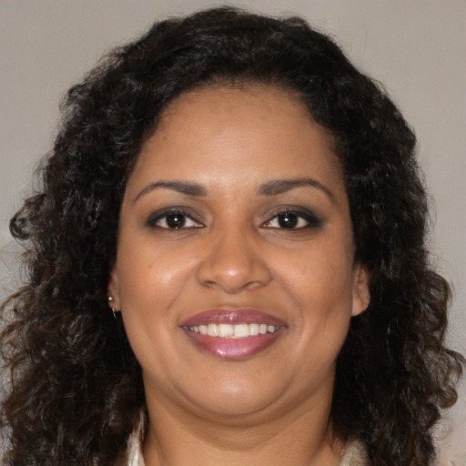Joyful black adult female with long  brown hair and brown eyes