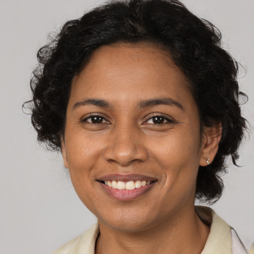 Joyful black adult female with long  brown hair and brown eyes